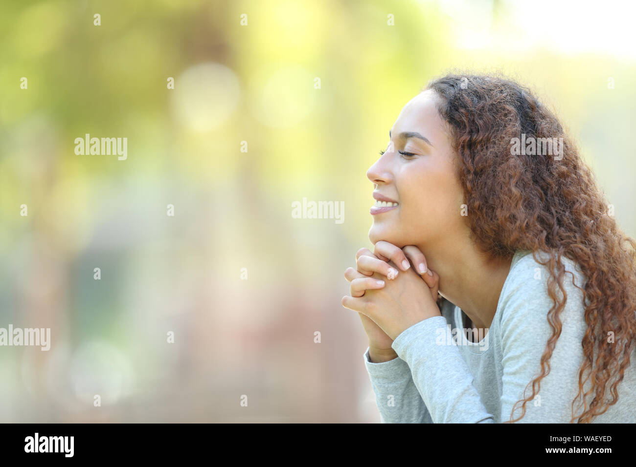 Seitenansicht Portrait Of Happy gemischten Rasse Frau, meditieren und atmen die frische Luft draußen in einem Park Stockfoto