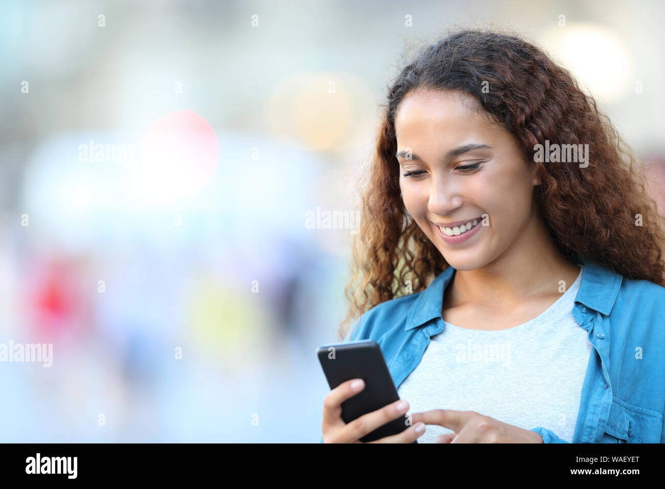 Happy gemischten Rasse Frau mit Smart Phone zu Fuß auf der Straße Stockfoto