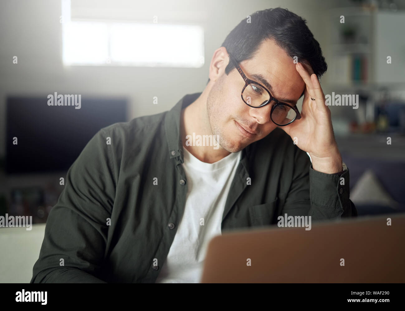 Mann mit Kopf mit seiner Hand an Laptop suchen Stockfoto