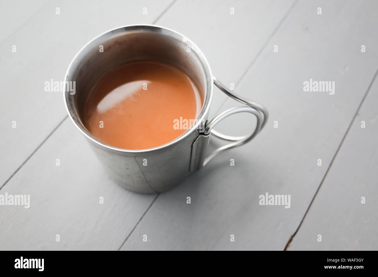 Edelstahl Becher Kaffee mit Milch steht auf einem weißen Holztisch, closeup Foto mit selektiven Fokus Stockfoto