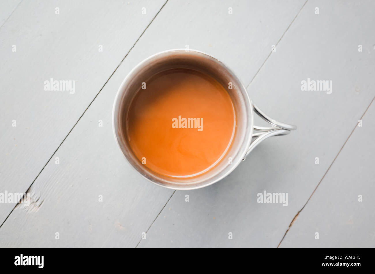 Edelstahl Becher Kaffee mit Milch steht auf einem weißen Holztisch, closeup Draufsicht Foto mit selektiven Fokus Stockfoto