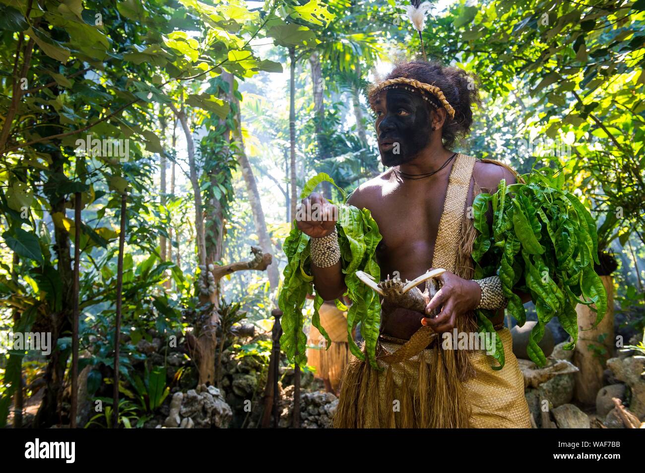 Traditionelle gekleideter Mann mit schwarzen Gesicht im Dschungel, Ekasup Cultural Village, Efate, Vanuatu Stockfoto