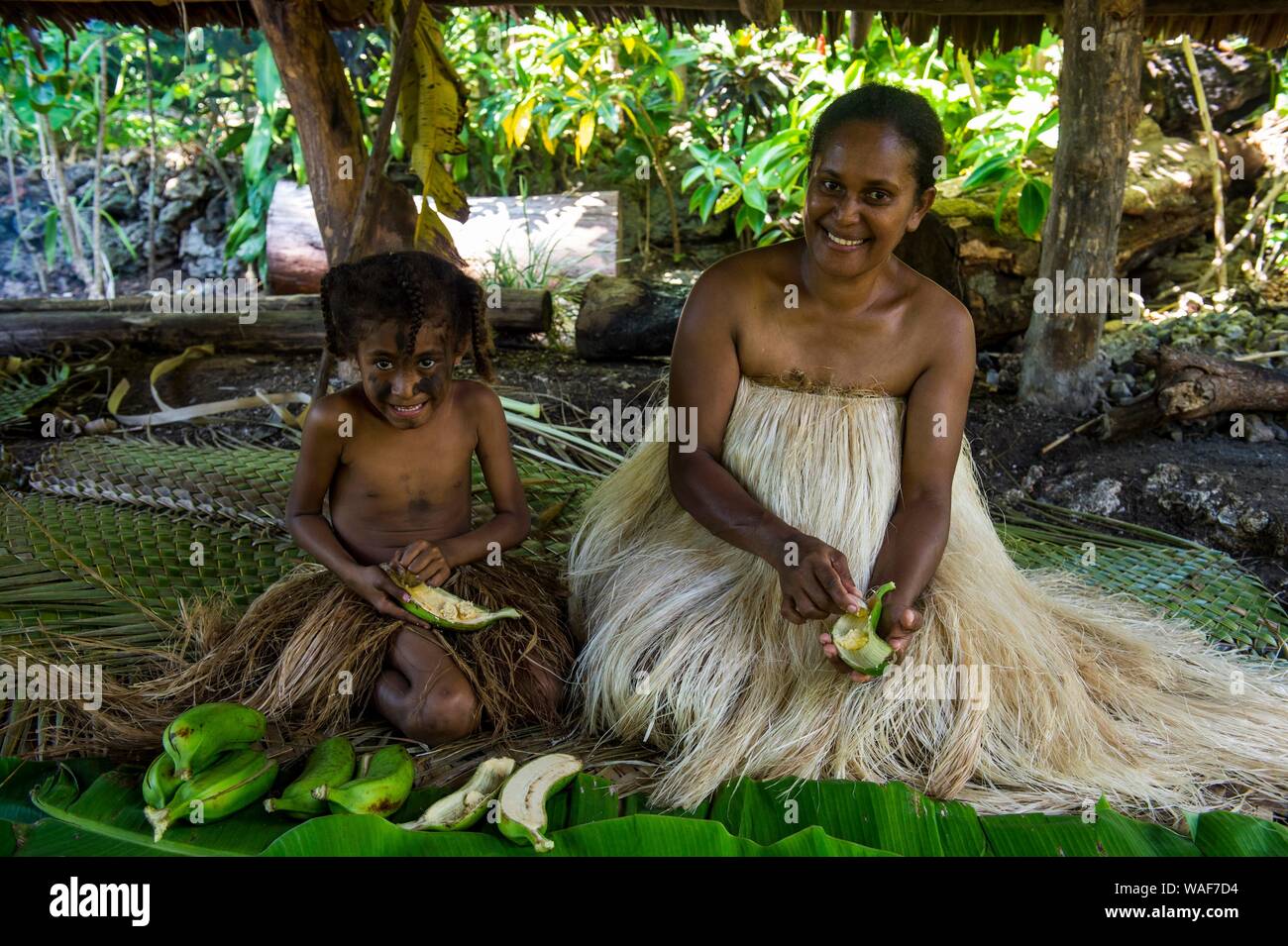 Frau mit ihrer kleinen Tochter Vorbereiten von traditionellen Speisen mit Bananen, Ekasup Cultural Village, Efate, Vanuatu Stockfoto