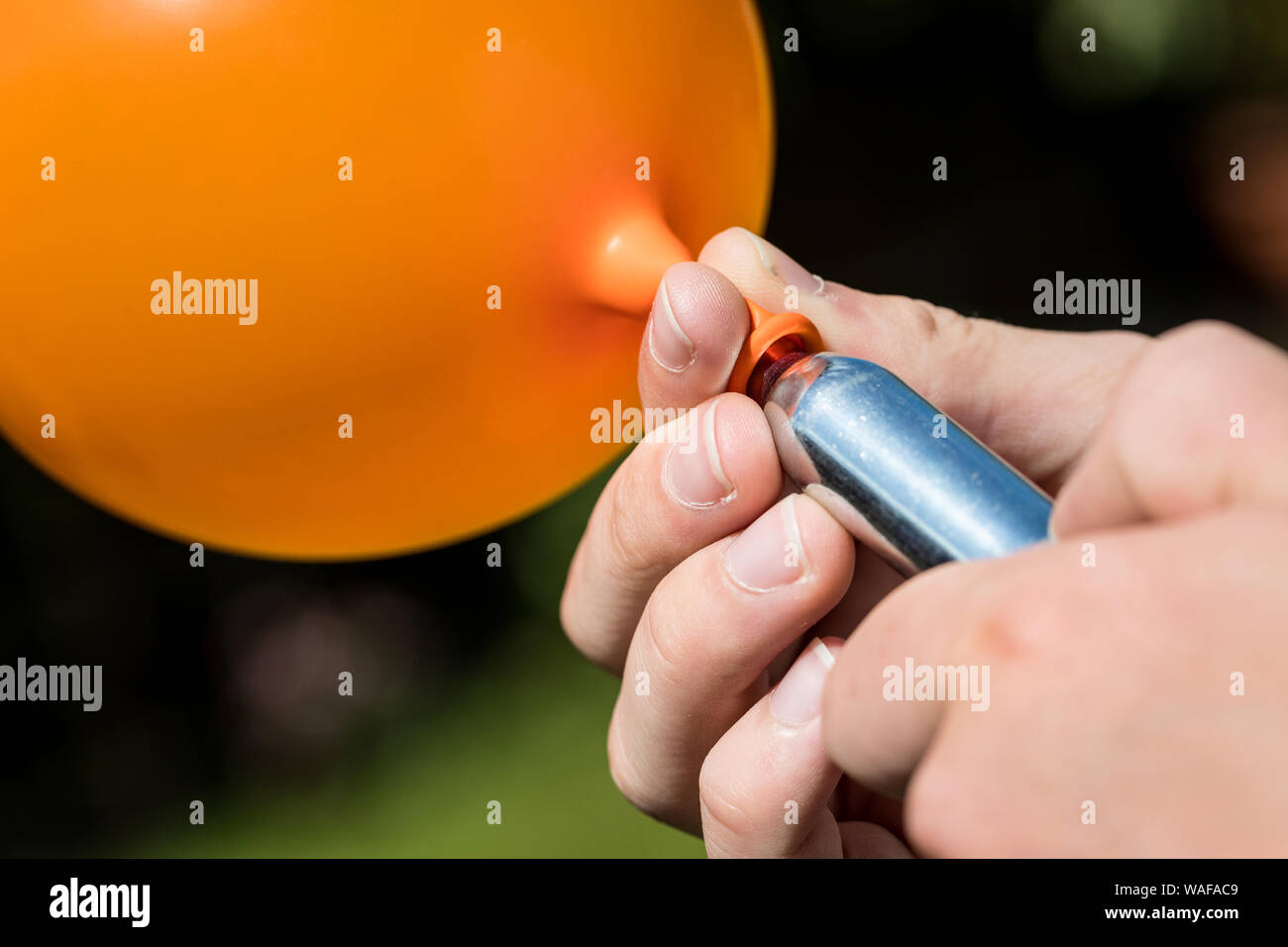 Ein Jugendlicher füllt einen Ballon mit Distickstoffoxid (Lachgas) auch als Hippie crack bekannt Stockfoto