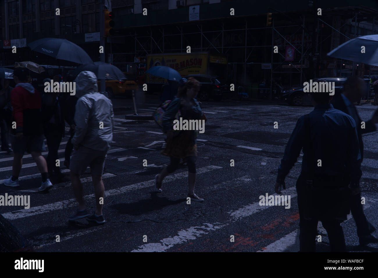 New York City, ca. 2019: Nacht über Manhattan zebrastreifen am Abend Fahrt im Regen. Poncho und Regenschirm Beläge halten Fußgänger d Stockfoto