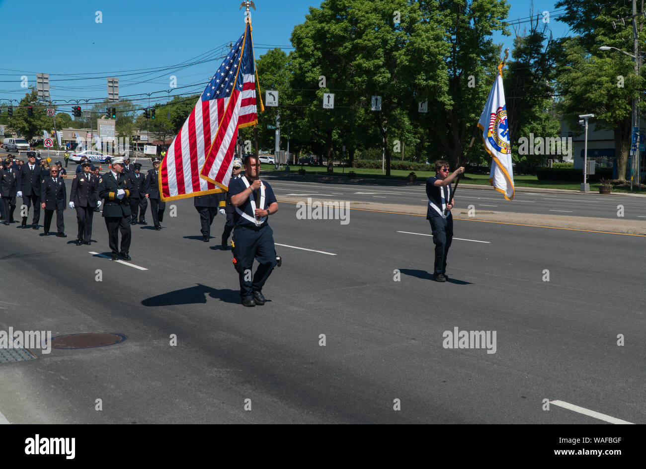 Long Island, NY - ca. 2019: Memorial Day Parade Feier, EMS und Feuerwehrleute März in Uniform die Straße runter, die amerikanische Flagge USA m zu Ehren Stockfoto