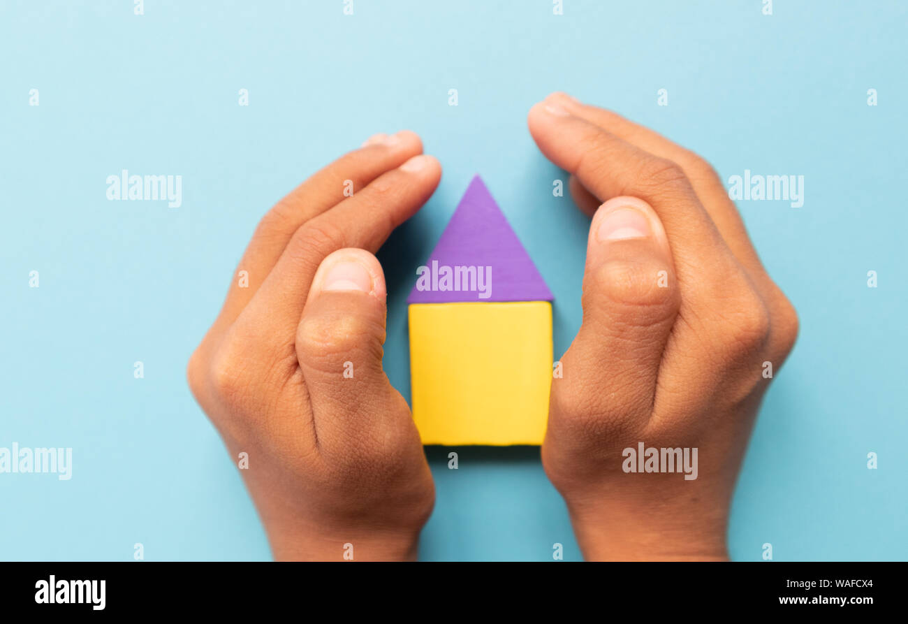 Kind Hände Surround ein buntes Holzhaus versicherung Konzept oder HOMEOWNERSHIP. Stockfoto