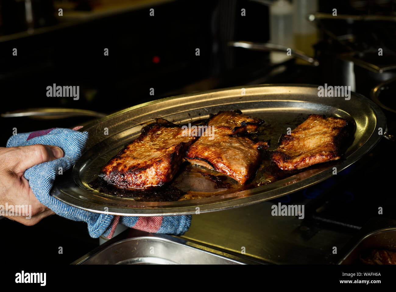 Nahaufnahme von einem Mann in einer professionellen Küche mit einem Tablett mit einigen Stücken gekocht Secreto iberico, Schweinefleisch Schnitt von spanischen iberischen Schwein Stockfoto