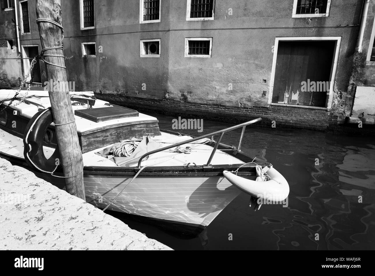 Altes Boot vertäut In einem schmalen Kanal entlang Gebäude, Venedig, Italien Stockfoto