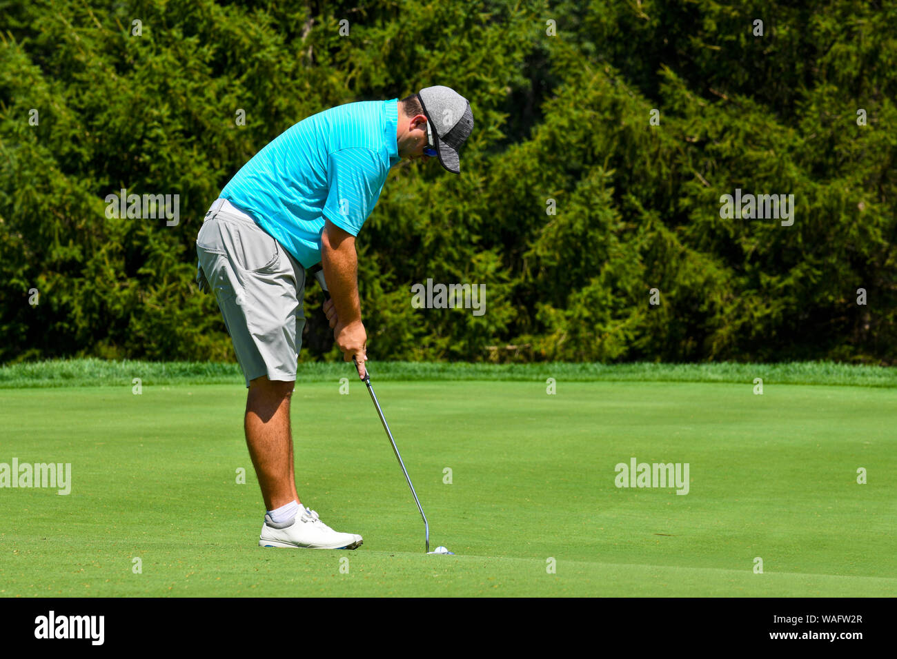 Junger Mann, Golf zu spielen auf der Suche nach Grün und die Konzentration auf seinen Schlag erschossen. Stockfoto