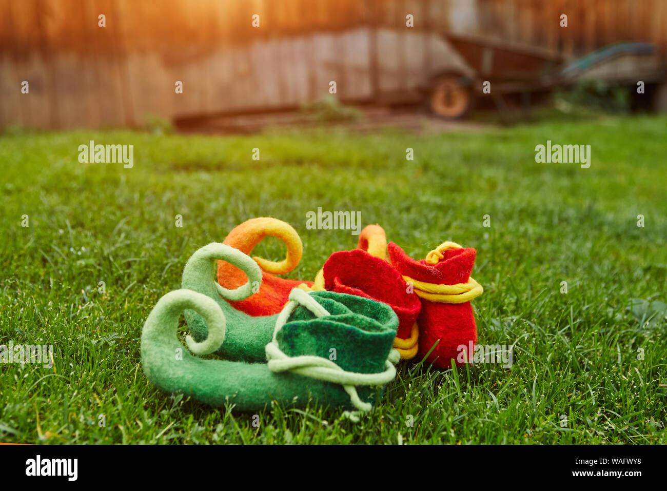 Schuhe Fabelwesen Stehend auf dem Gras, auf dem Hintergrund einer Holzhütte und einem kleinen dreirädrigen Warenkorb Stockfoto