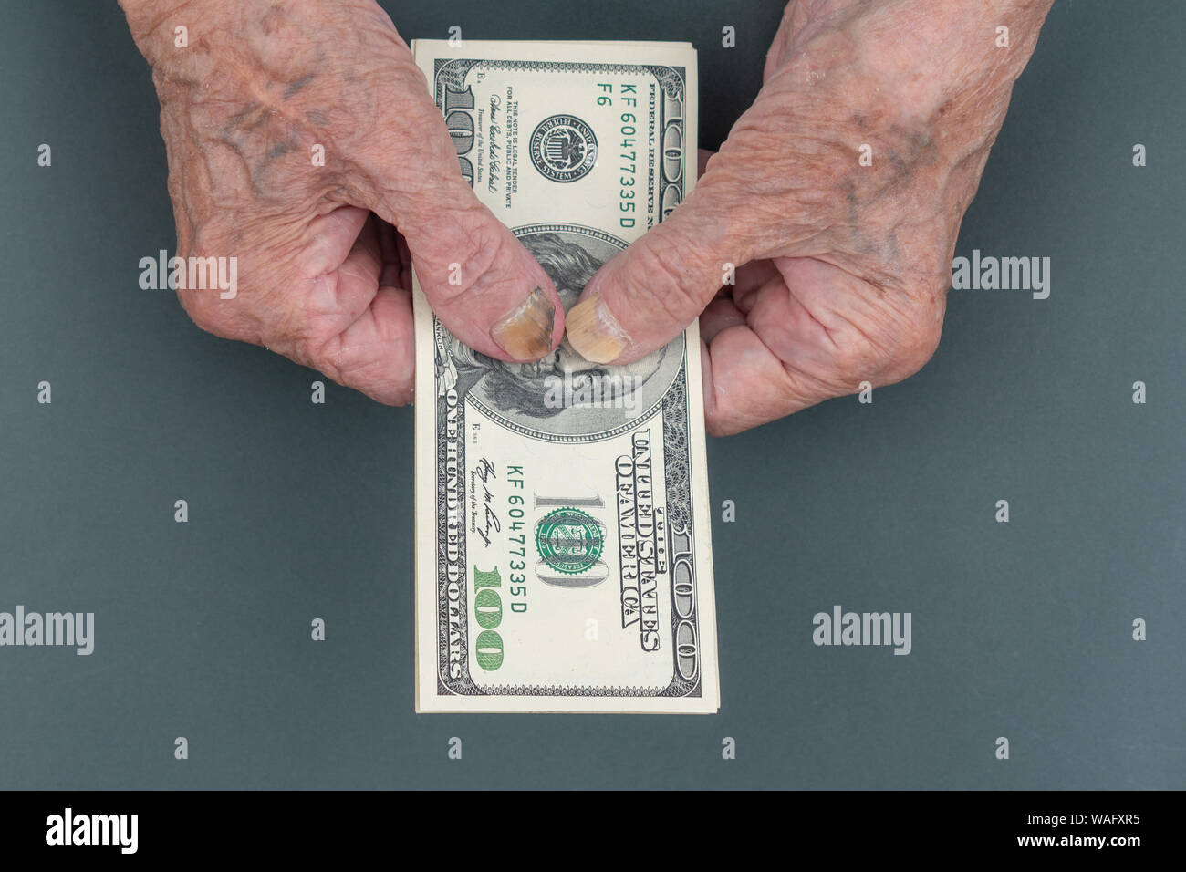 Armen alten Frau zählt einige amerikanische Dollar in der Hand. faltigen Hände einer alten Frau. Zählen von Geld, Wirtschaft Konzept, das Geld zu teilen. Thri Stockfoto
