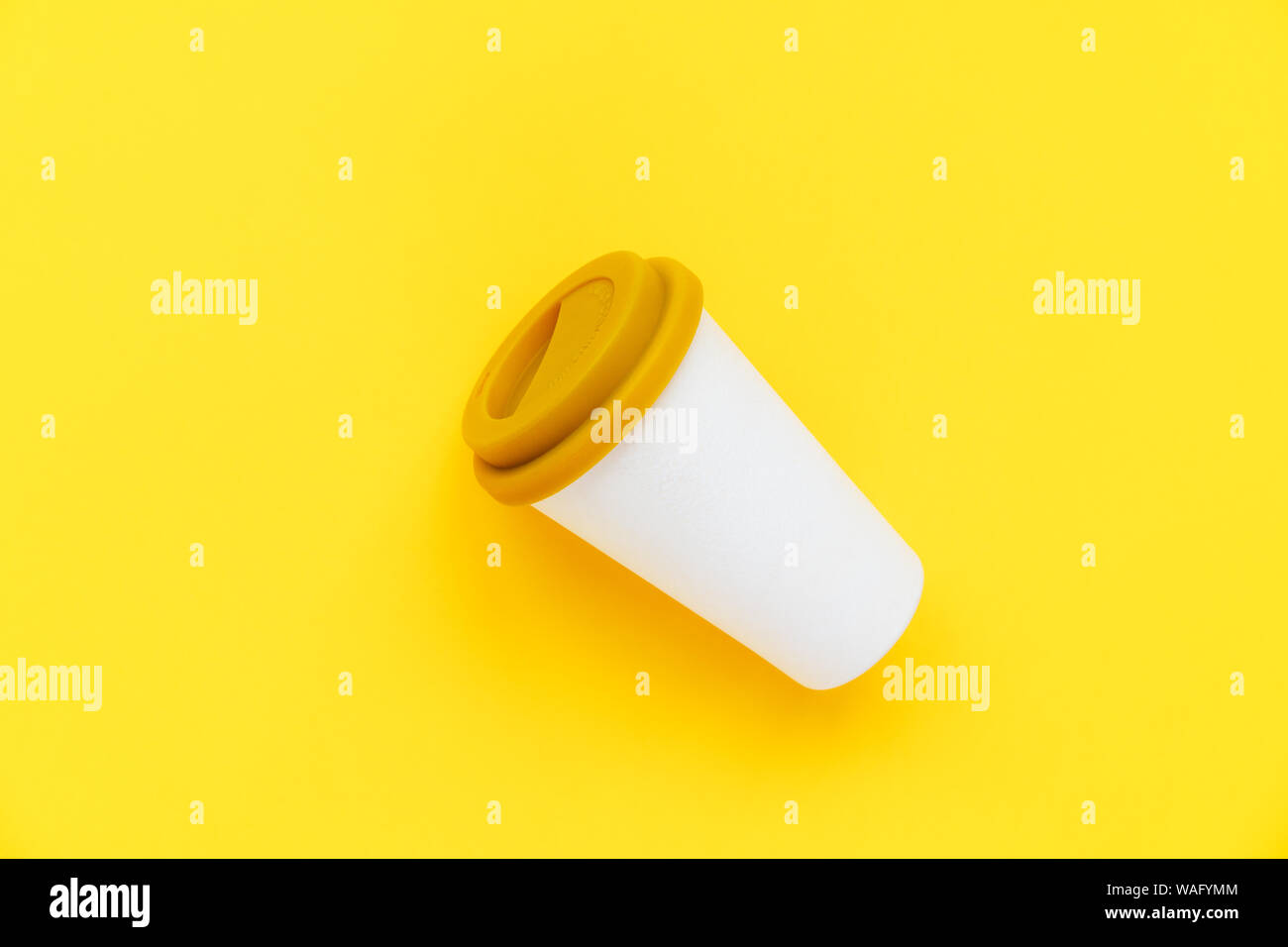 Weiß Bambus Kaffee Tasse mit einem gelben Gummi Deckel auf einem gelben Hintergrund zu gehen Stockfoto