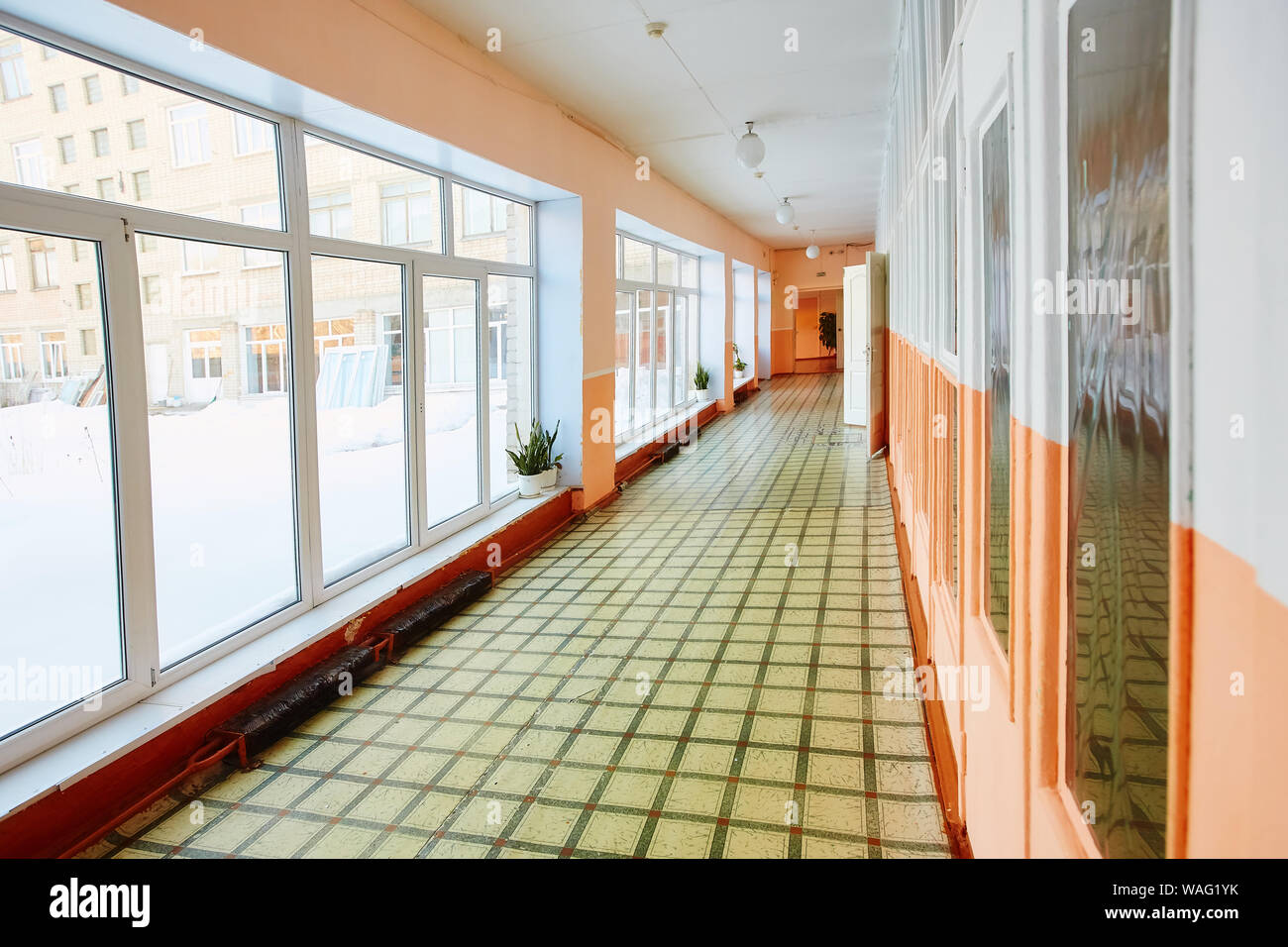 Blick in eine alte Schule oder Bürogebäude Korridor, leere schmal, hoch und lang, mit vielen Türen und Fenster. Das Interior Design ein Stockfoto