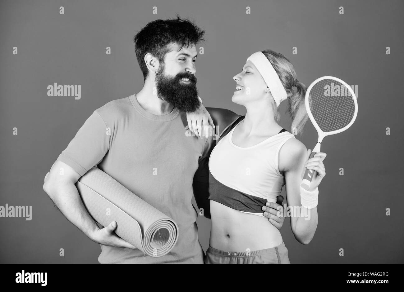 Wir sind alle zusammen. Sport Paar. Glückliche Frau und bärtiger Mann trainieren Sie im Fitnessraum. Sportliches paar Training mit Fitness Matte und Tennisschläger. Starke Muskeln und Körper. Sportlichen Erfolg. lieben den Sport. Stockfoto