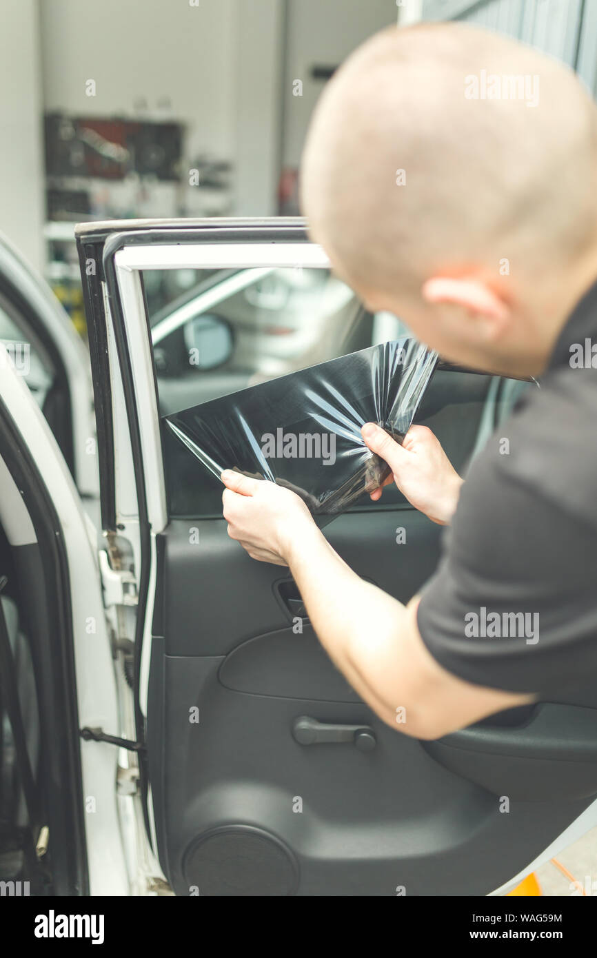 Mitarbeiter Entfernen von alten, dunklen Auto Fenster Glas Folie in der  Garage Stockfotografie - Alamy