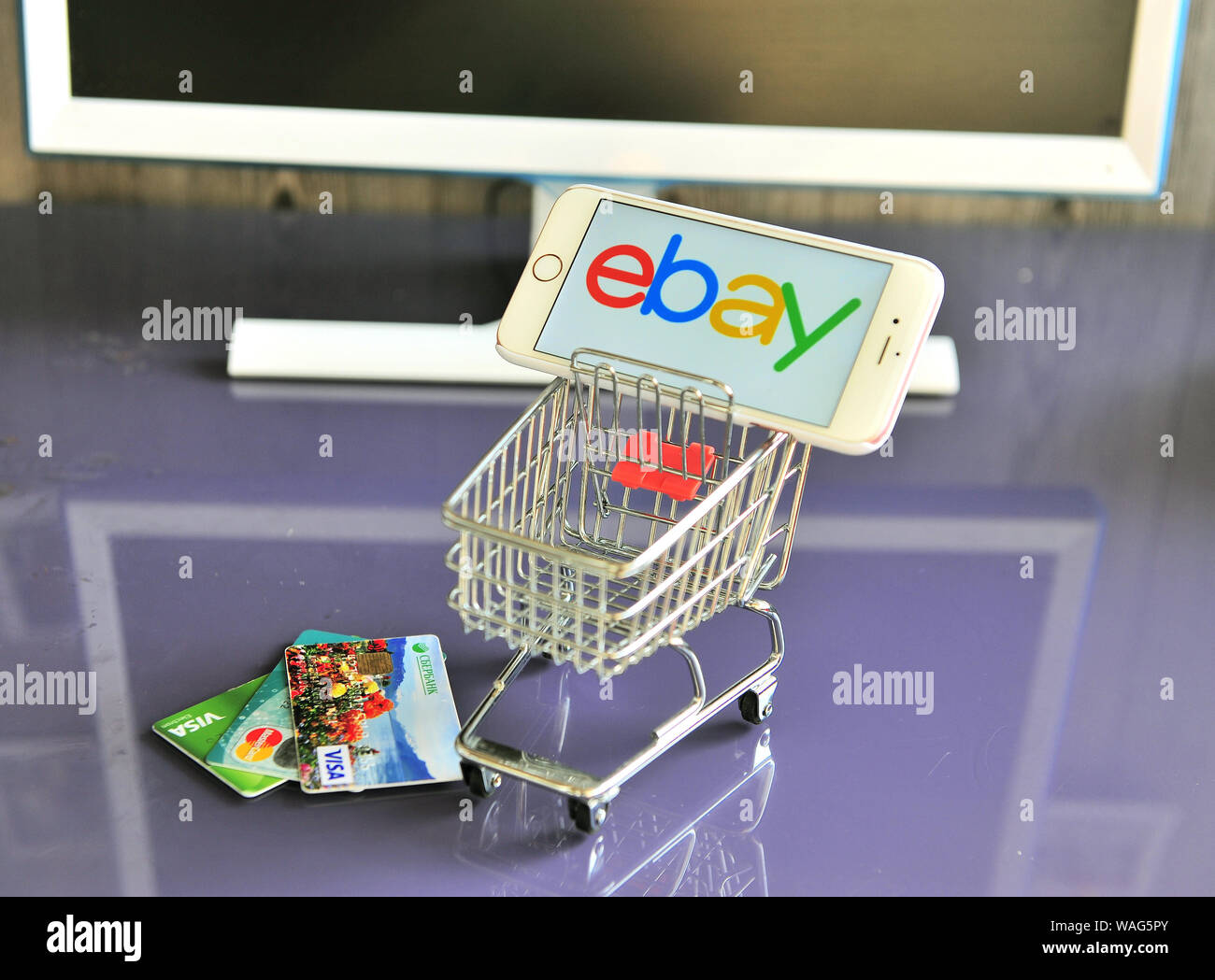 Jaroslawl, Russland - 20. August 2019: Handy mit ebay Logo im Warenkorb und Kreditkarten auf dem Tisch. Stockfoto