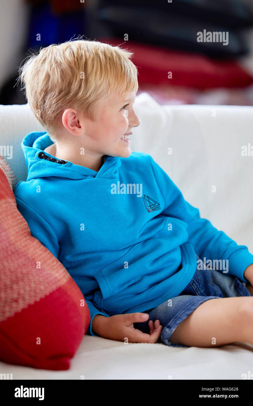 Junge lächelnd Sitzen auf einem Sofa Stockfoto