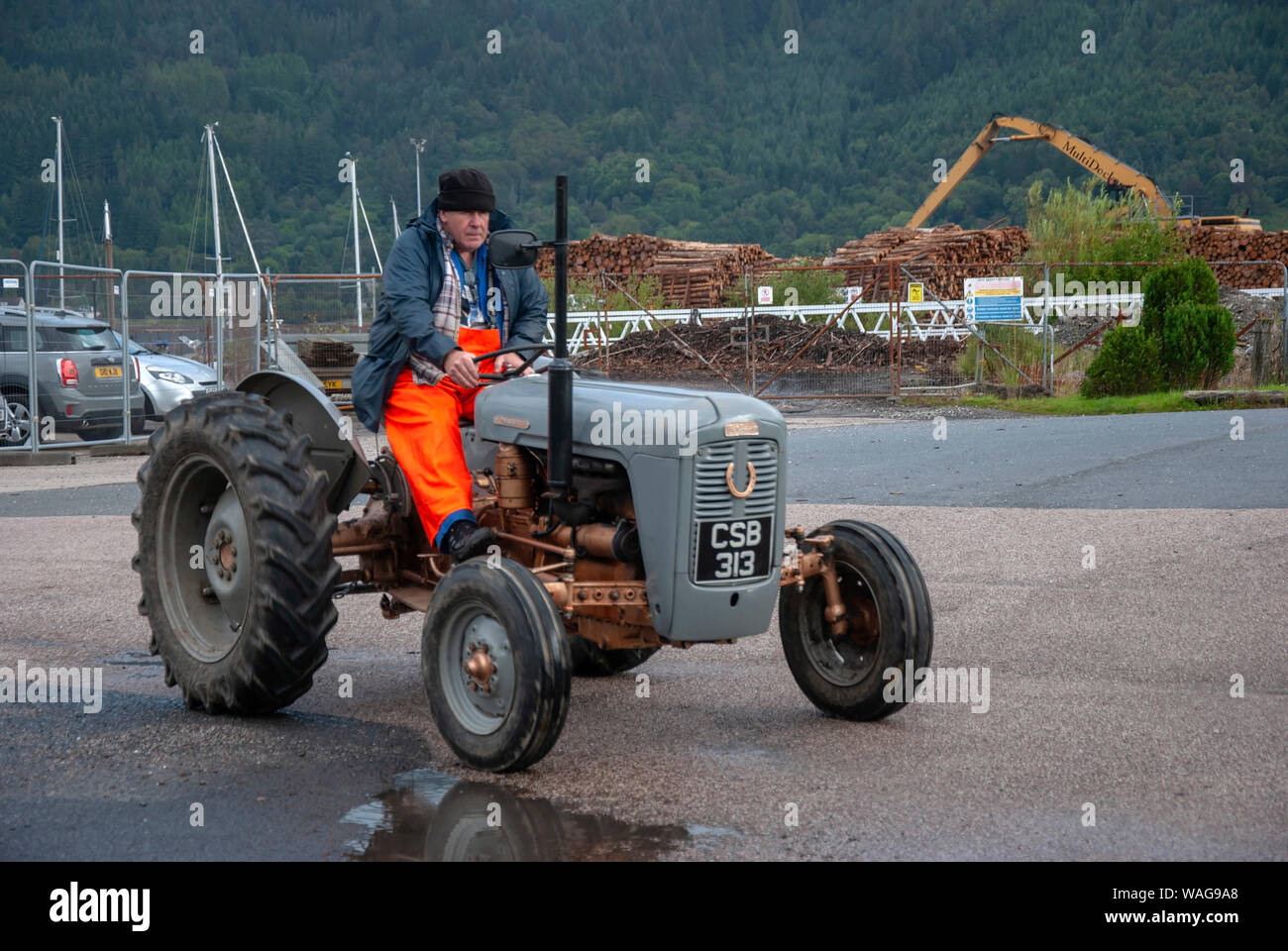 Mann, der 1957 Vintage Massey Ferguson FE 35 Gold Bauch Grey Fergie Traktor vorne abseits Treiber Seitenansicht männlichen orange wasserdichte Hosen veteran H Stockfoto