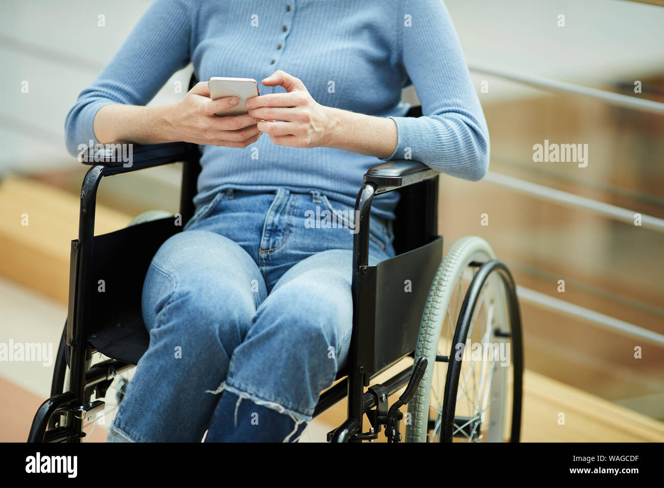 Nahaufnahme der behinderte junge Frau in Freizeitkleidung sitzt im Rollstuhl und Kommunikation online auf Handy Stockfoto