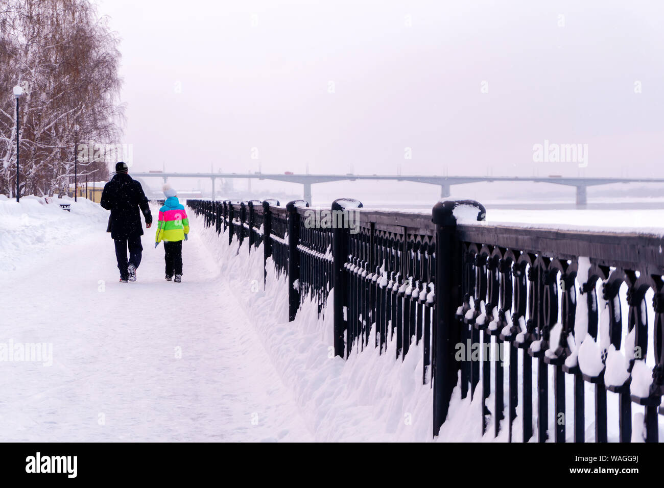 Ein Mann und ein Mädchen sind zu Fuß entlang der Winter Quay, Jacke des Mädchens ist der einzige helle Punkt in die verschneite Landschaft Stockfoto