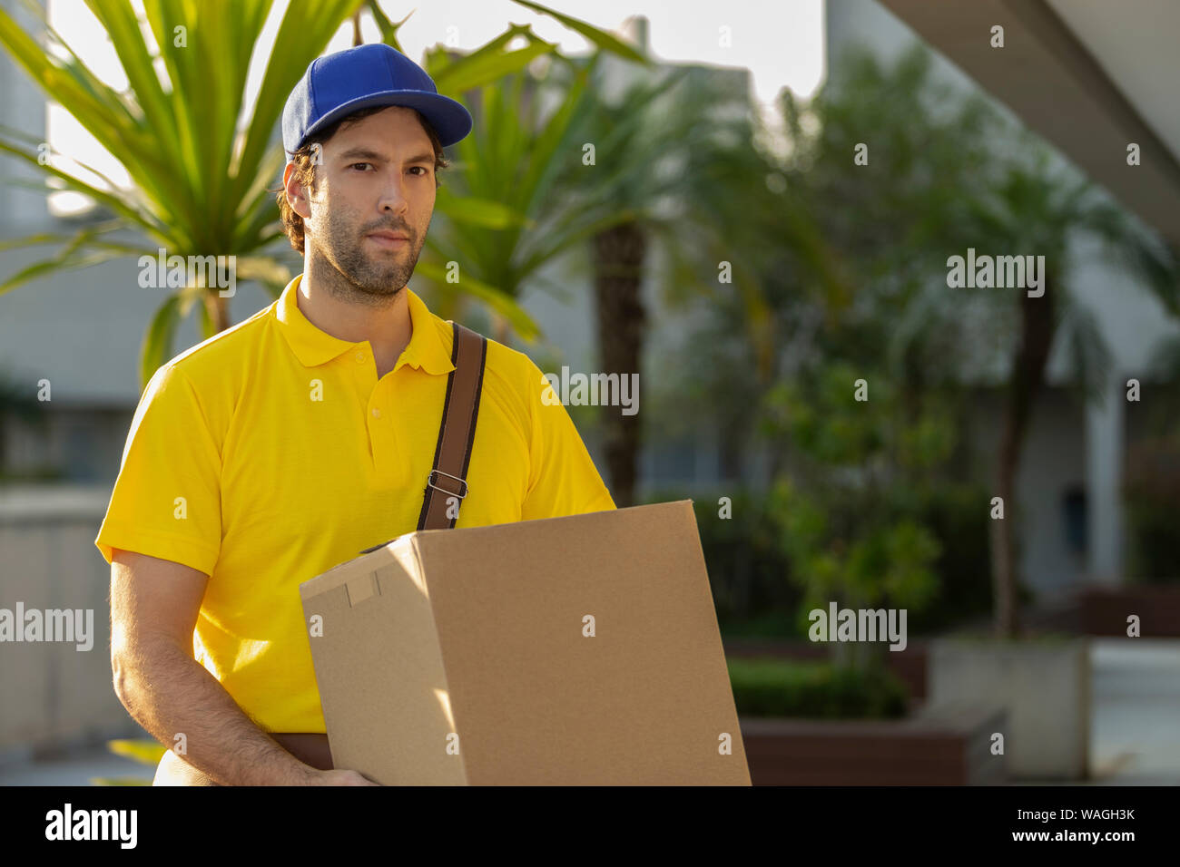 Brasilianische Mailman liefert ein Paket auf der Straße. Kauf über Internet zu Hause geliefert. Stockfoto