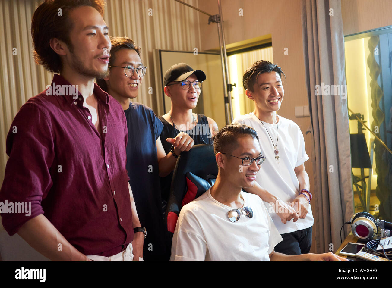 Junge Mitglieder einer asiatischen Rock Band gemeinsam Bearbeiten von Musik mit dem Computer Stockfoto