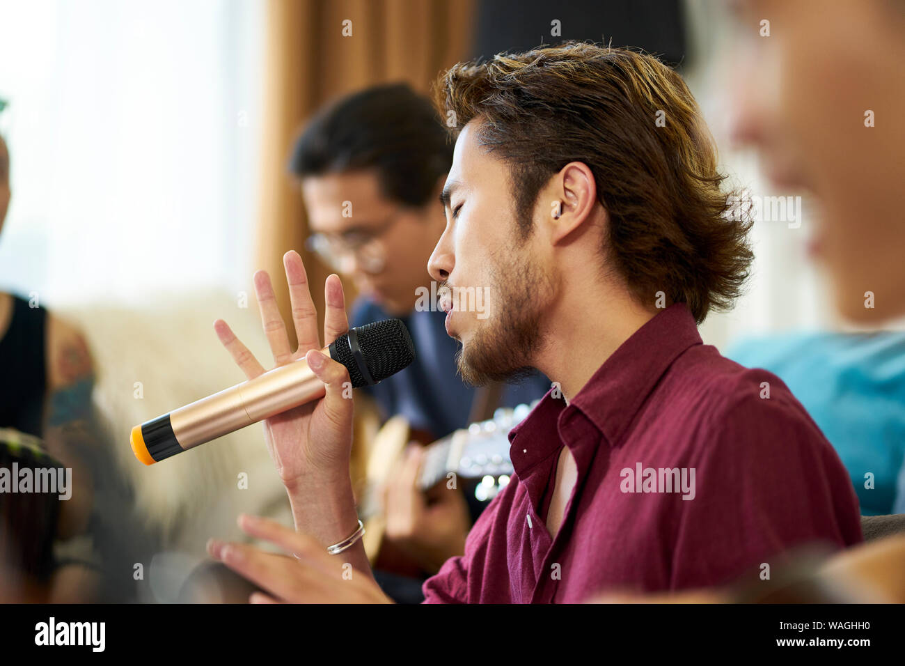 Jungen asiatischen erwachsene Männer Rock Band Mitglieder Proben singen die Musikinstrumente im Wohnzimmer eines Hauses Stockfoto