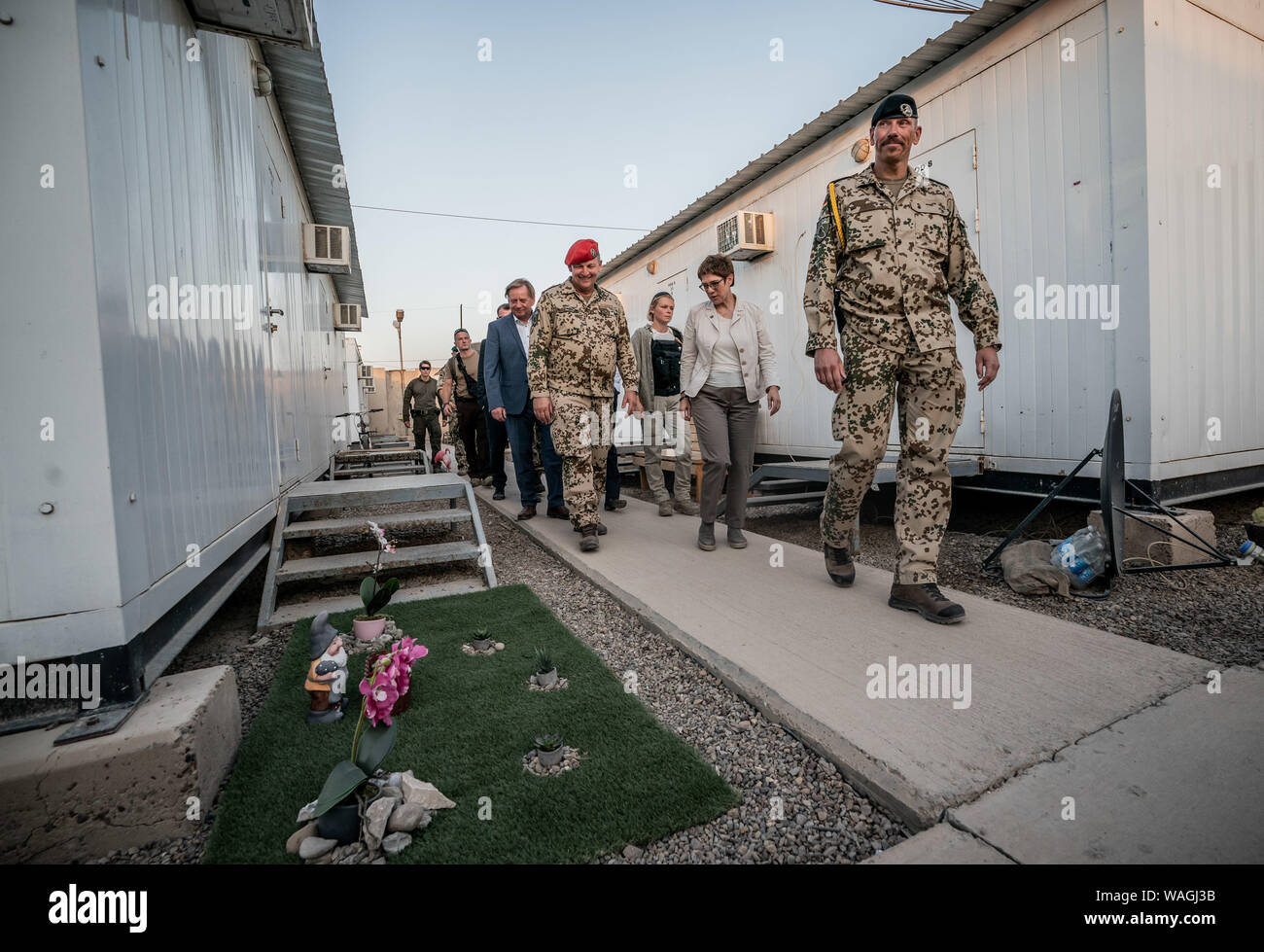 Bagdad, Irak. 20 Aug, 2019. Annegret Kramp-Karrenbauer (CDU, 2. von rechts), Minister für Verteidigung, Spaziergänge durch die Unterkunft mit Bundeswehr Oberst Jörg Wellbrink (4. von rechts) beim Besuch der deutschen Soldaten in die internationalen militärischen camp Camp Taji und sieht einen "Garten", in der ein gartenzwerg auf Kunstrasen steht. Der Minister und CDU-Chefin ist die Durchführung von politischen Gesprächen in der Hauptstadt Bagdad und ist es, die deutschen Soldaten, die in die Ausbildung lokaler Kräfte im Land beteiligt sind. Quelle: Michael Kappeler/dpa/Alamy leben Nachrichten Stockfoto