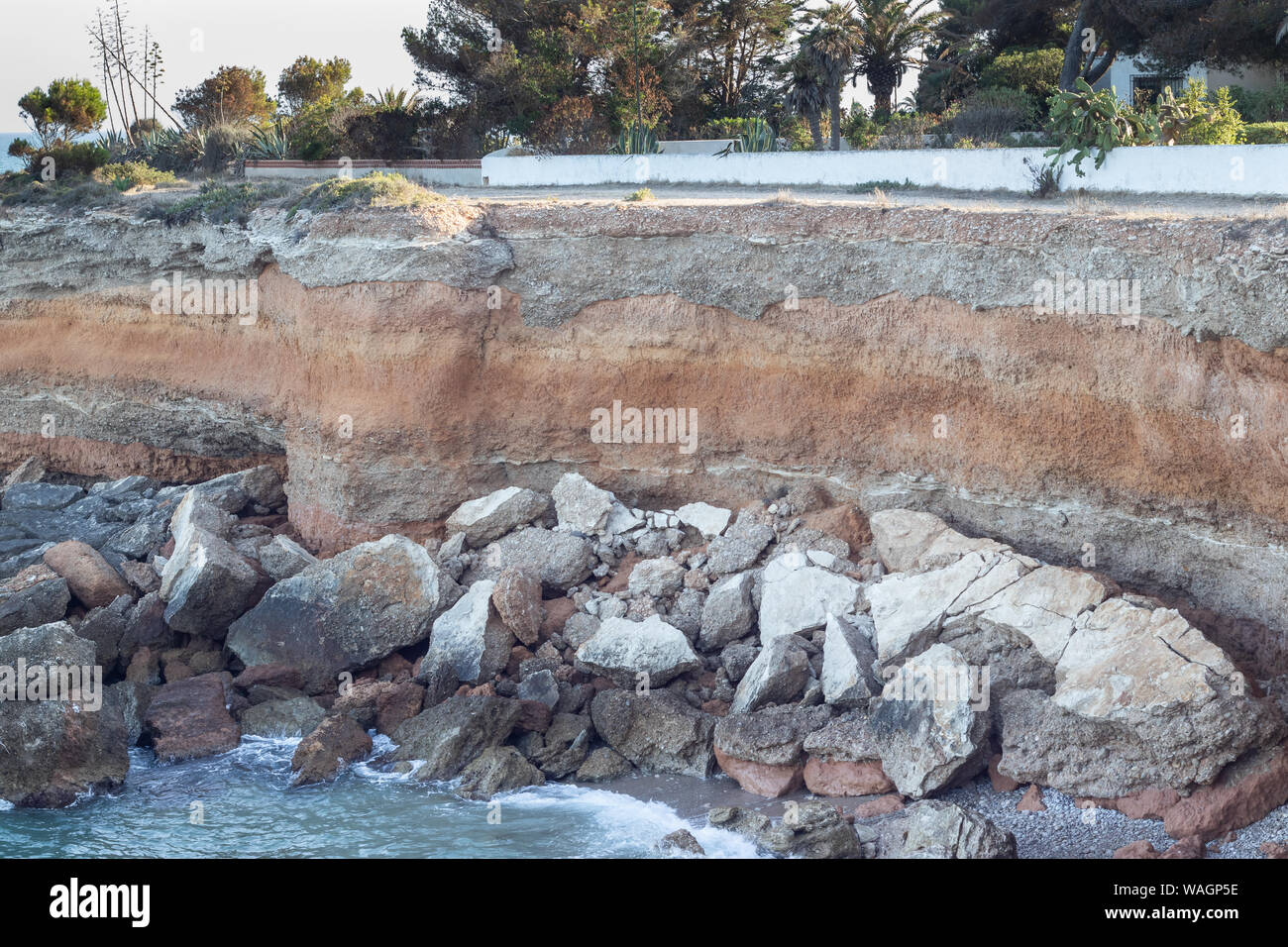 Felsen stürzte in einen Strand unter einem Felsen Stockfoto