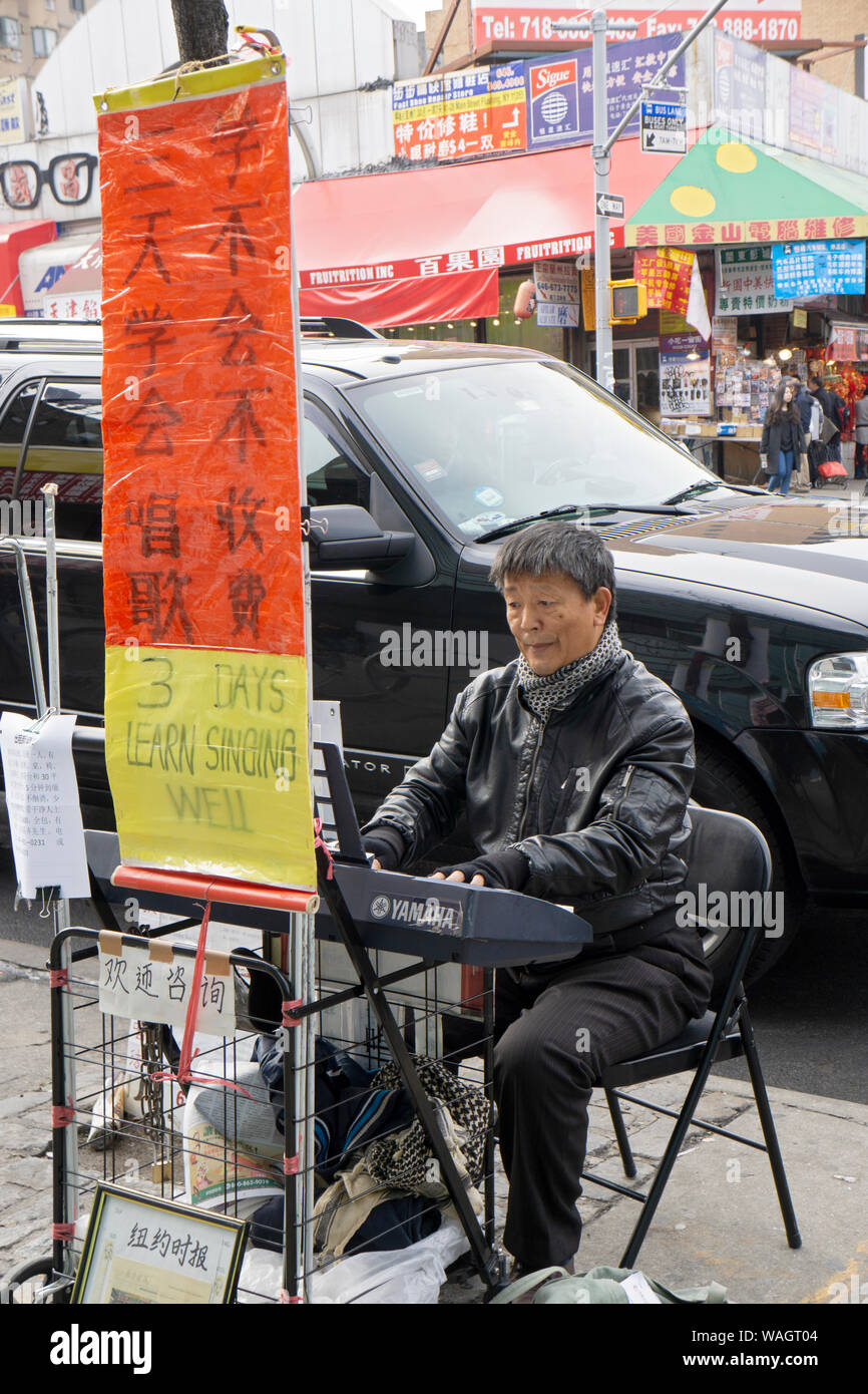 Ein koreanischer Mann spielt das Klavier auf der Main Street An einem Winternachmittag in Flushing, Queens, NY und Werbung Gesangsunterricht. Stockfoto