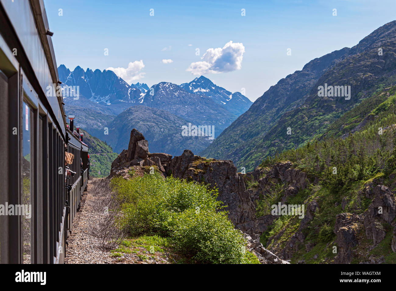 Eine Schmalspurbahn entlang White Pass Canyon in Richtung skagway Alaska mit Bergspitzen im Hintergrund Stockfoto