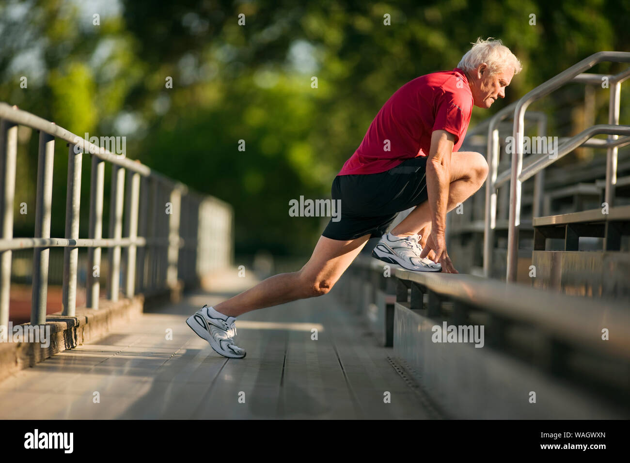 Reifer mann Aufwärmen mit erstreckt sich auf zuschauertribünen. Stockfoto