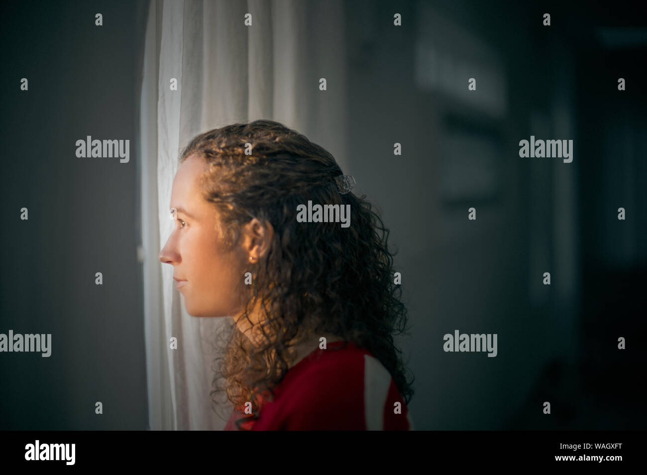 Junge Frau aus dem Fenster schauen. Stockfoto