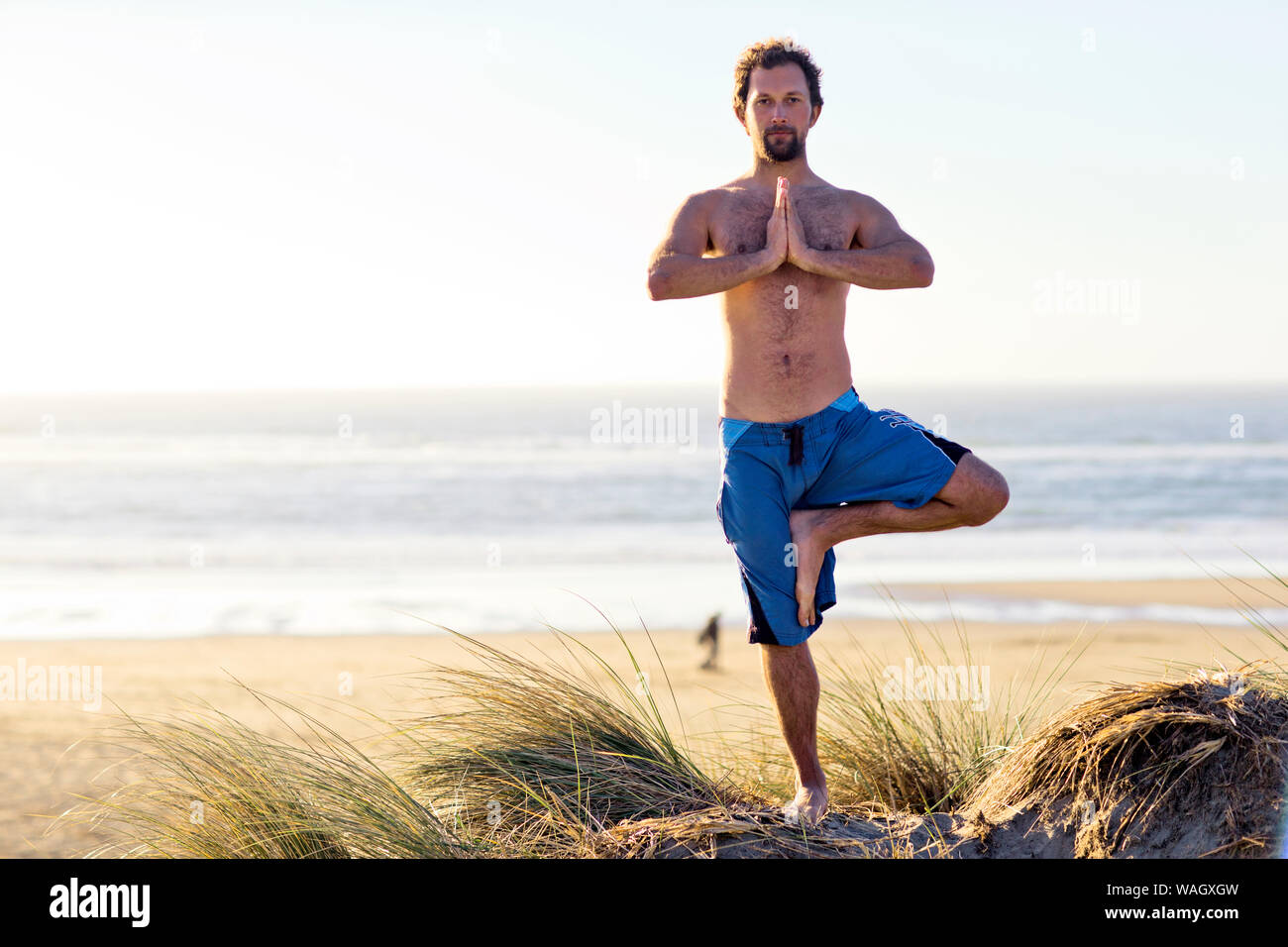 Mann in Yoga pose am Strand. Stockfoto