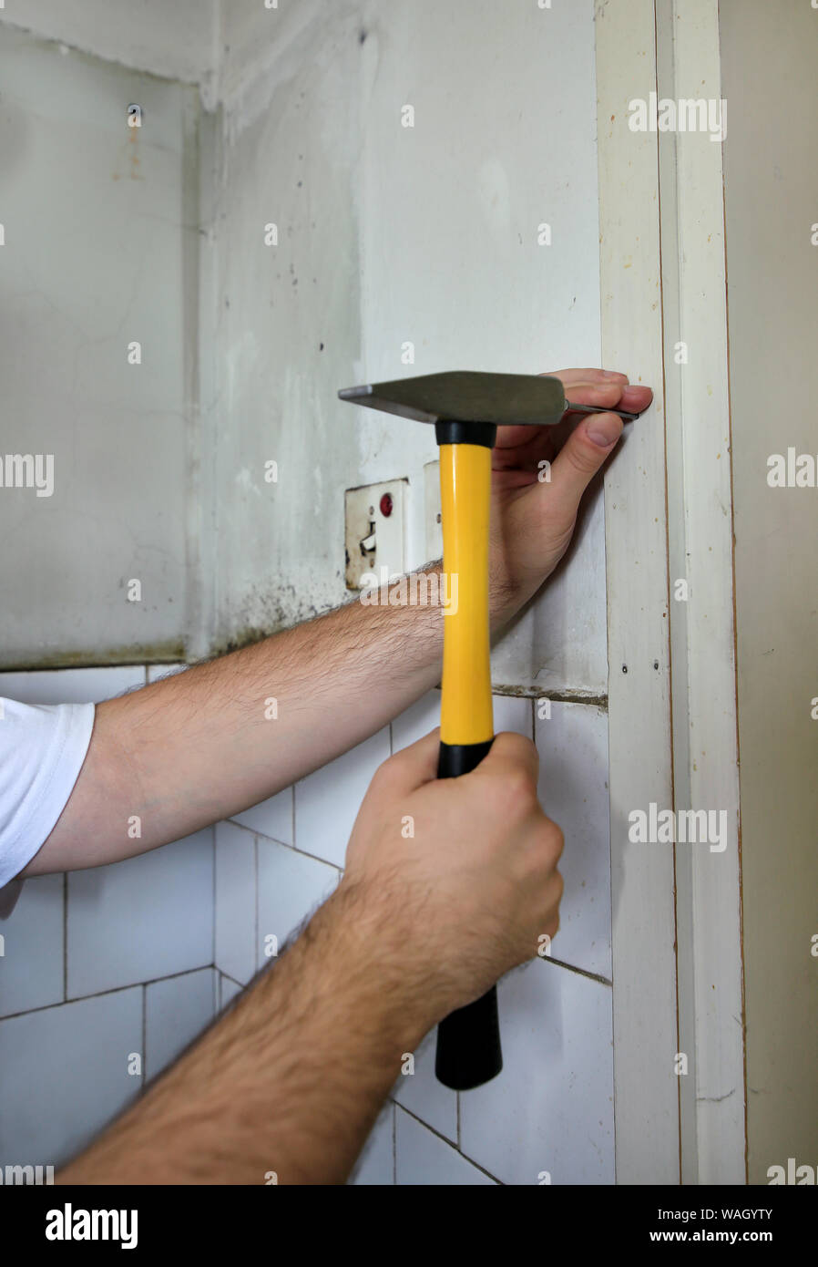 Bauarbeiter und Handwerker arbeiten auf Renovierungsarbeiten. Builder mit gelben Hammer und Nägel, einen Nagel in die Wand der Küche Tür. Stockfoto