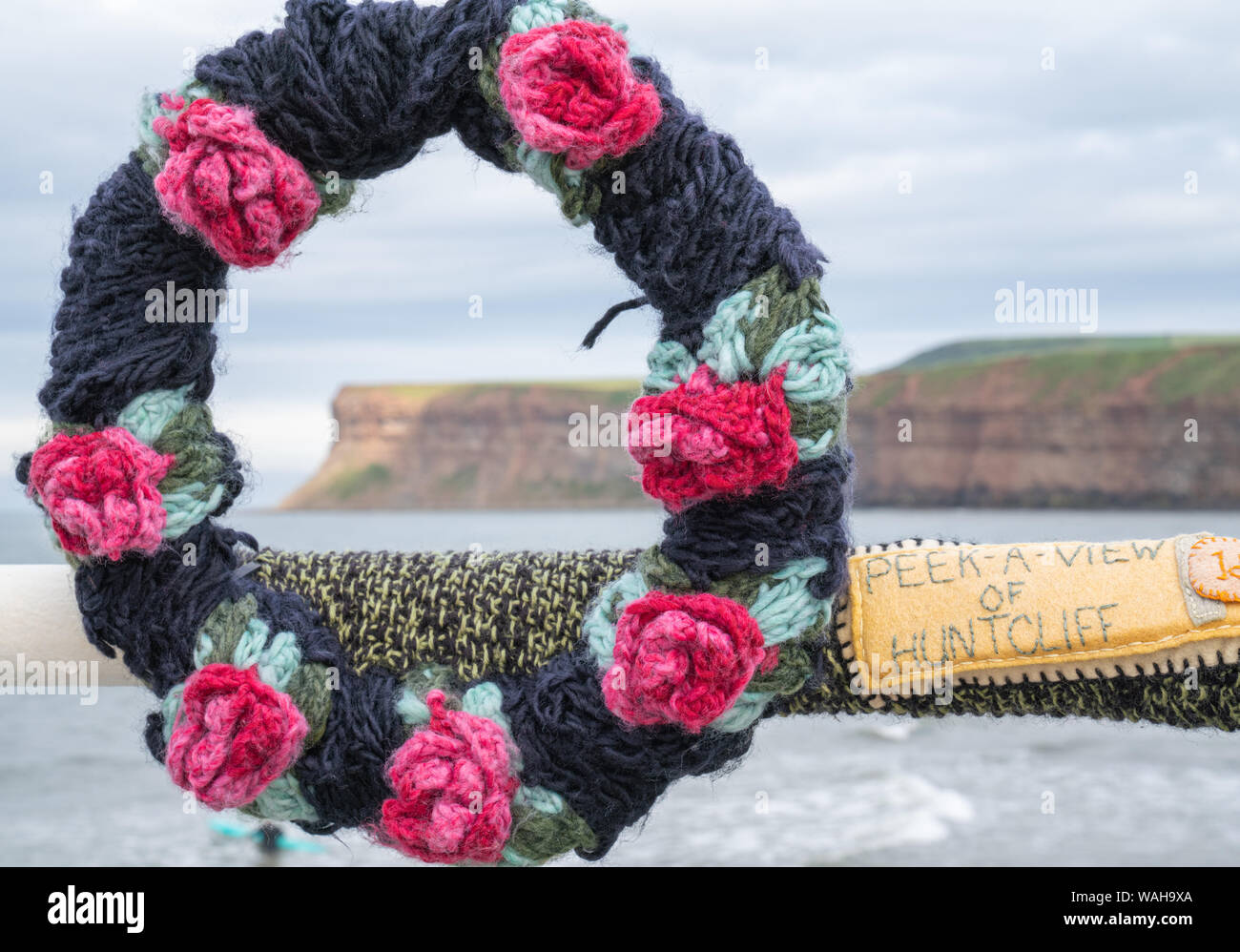 Ein Garn Bombardierung Installation eines Gestricken Kranz aus Rosen framing Huntcliff, erstellt der 150. Jahrestag der Pier in Saltburn zu feiern. Stockfoto