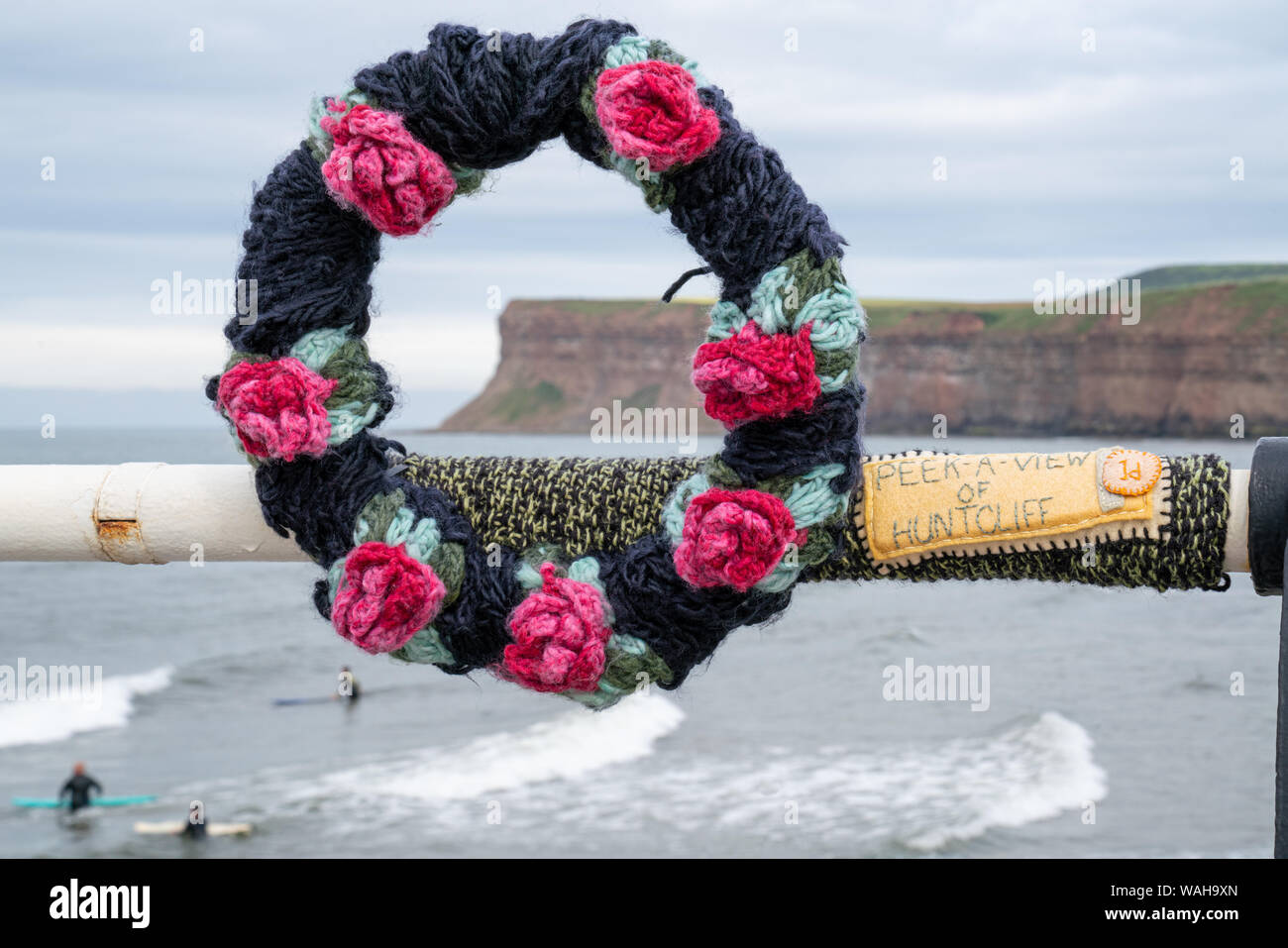 Ein Garn Bombardierung Installation eines Gestricken Kranz aus Rosen framing Huntcliff, erstellt der 150. Jahrestag der Pier in Saltburn zu feiern. Stockfoto