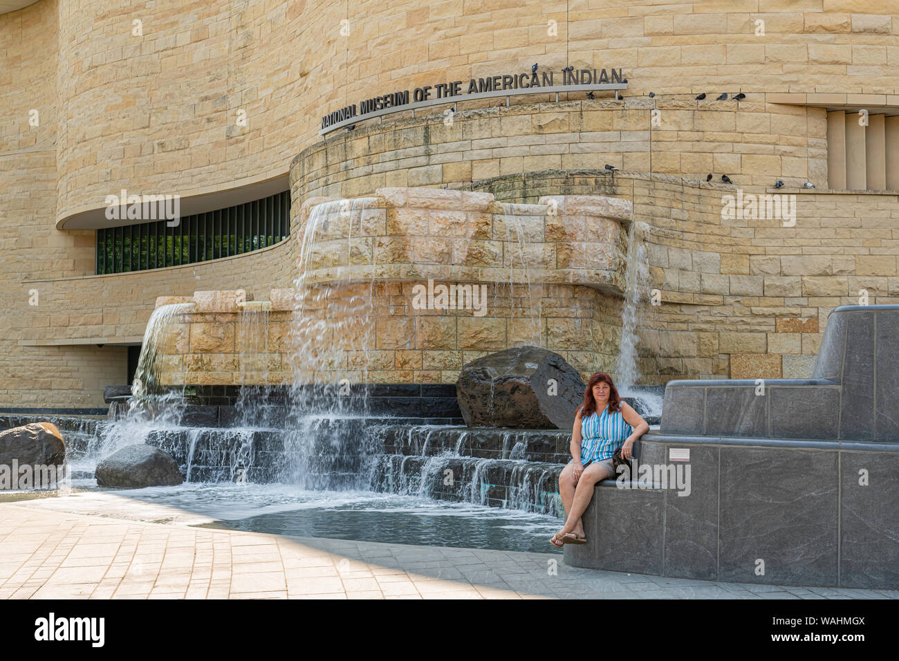 Washington DC, USA. 29.07.2019. Frau sitzt in der Nähe von Wasserfall am nationalen Museum der amerikanischen Indianer. Stockfoto