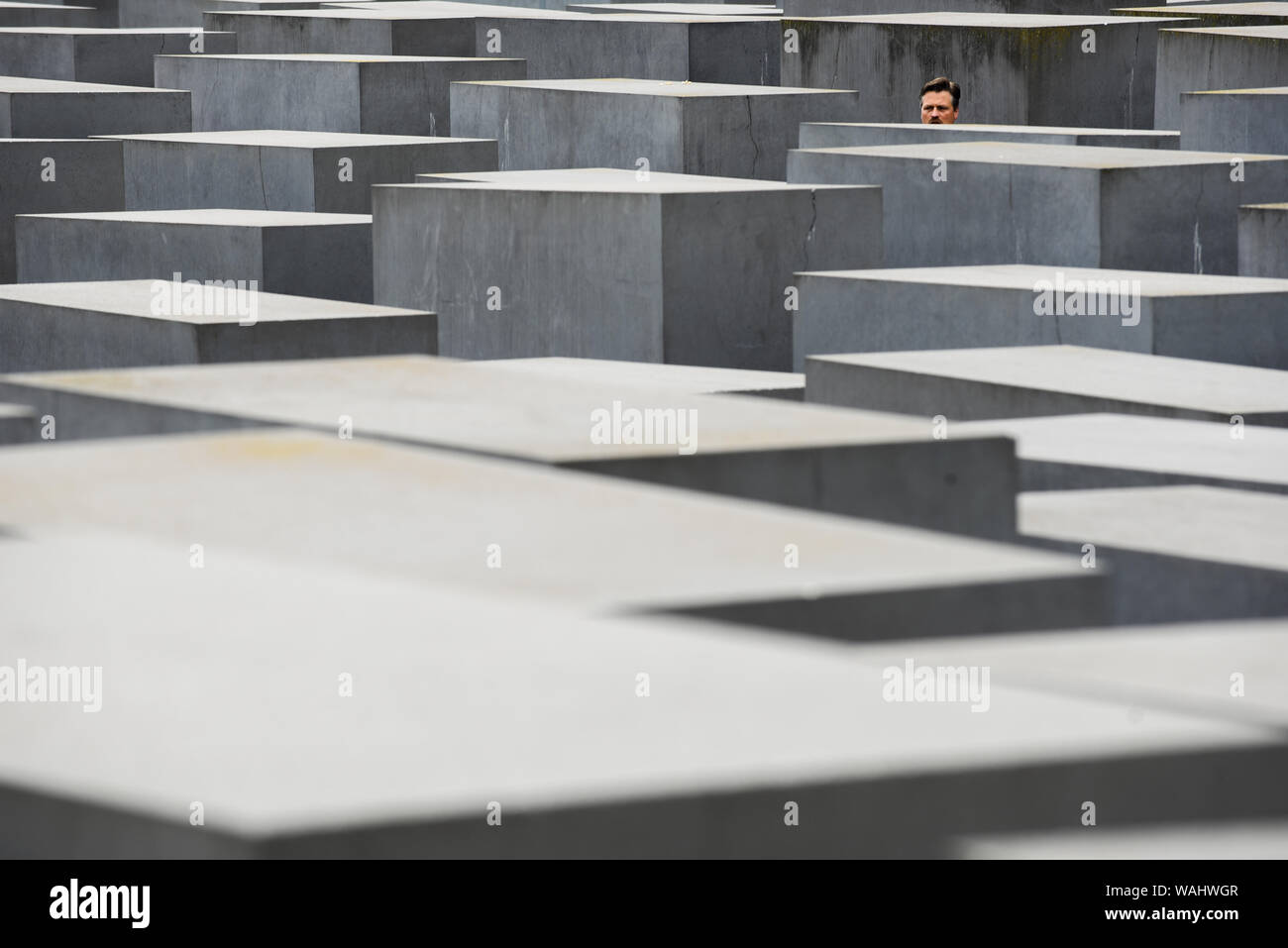 Die Besucher gehen durch Hunderte von betonplatten oder Der telae "Teil des Denkmals für die ermordeten Juden Europas "Holocaust Mahnmal" südlich des Brandenburger Tors. Holocaust Mahnmal wurde von amerikanischen Architekten Peter Eisenman entworfen, auf einer Fläche von 19.000 Quadratmetern von 2711 Betonplatten abgedeckt oder telae'. Stockfoto