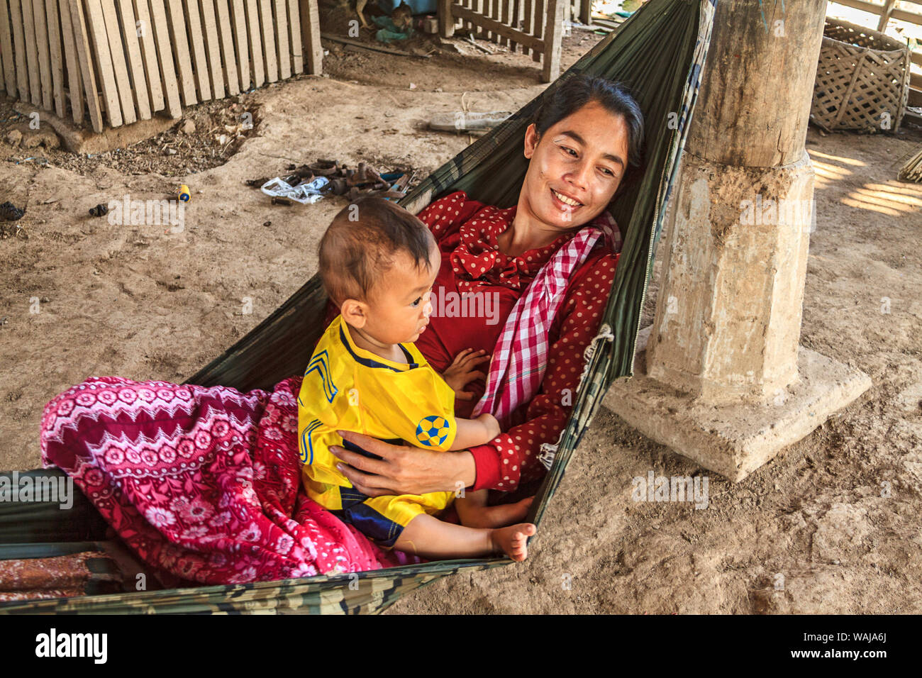 Kratie, Kambodscha. Junge Cham Mutter in einer Hängematte mit ihren Toddler Sohn in einem Dorf auf dem Mekong Fluss sitzen. Die Cham sind die größte ethnische Minderheit in Kambodscha und sind meist muslimischen. (Redaktionelle nur verwenden) Stockfoto