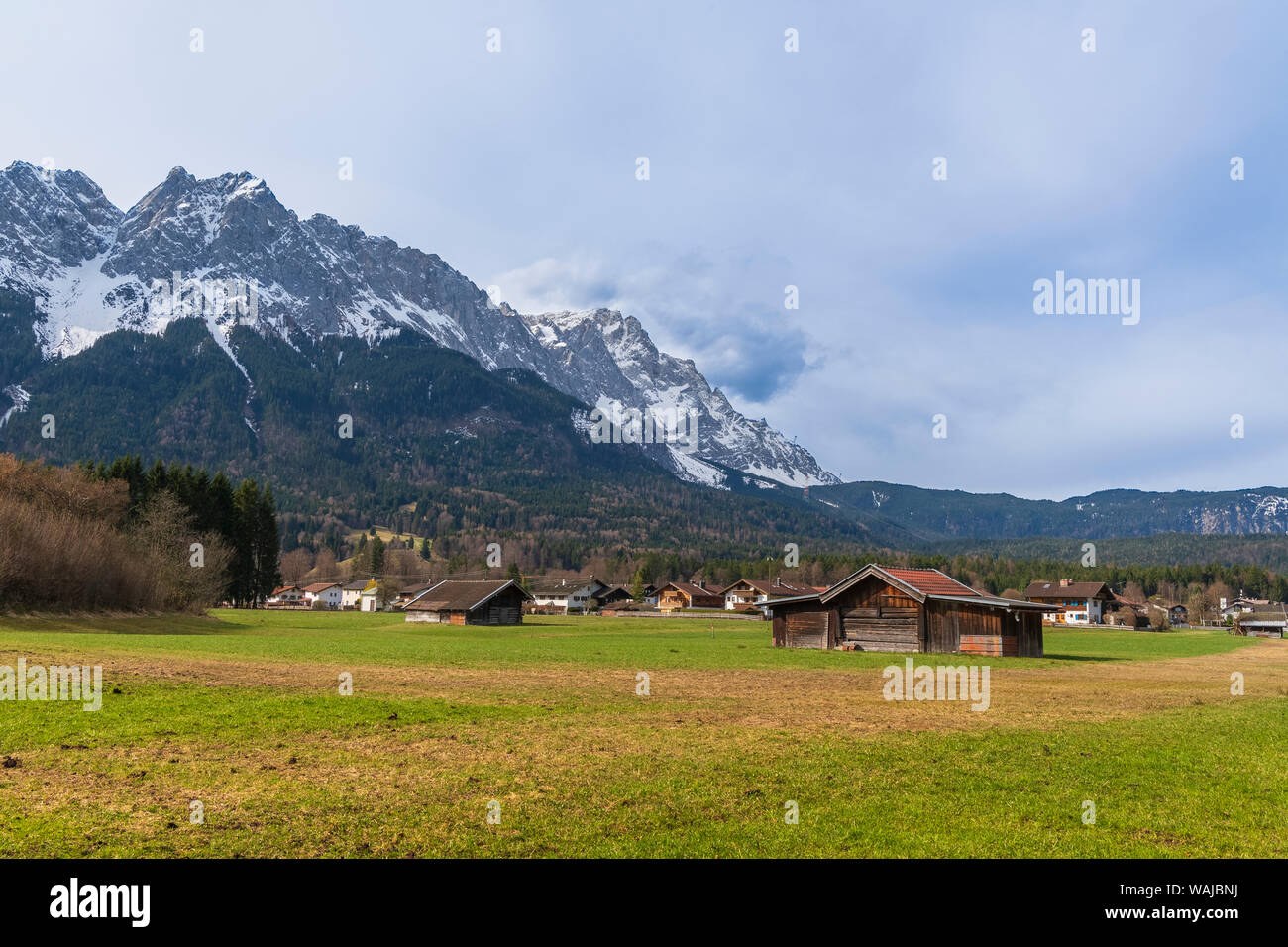 Bewirtschaftete Felder in der Ortschaft Grainau am Fuße der Alpen mit der Zugspitze im Hintergrund. Stockfoto