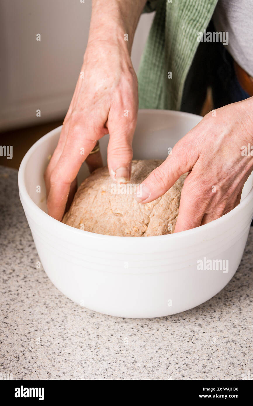 Frau drehen Brot Teig in eine gebutterte Schüssel, oben und unten zu versichern sind leicht mit Butter bestrichen, in der Vorbereitung für die Gekeimten Weizen Brot. (MR) Stockfoto