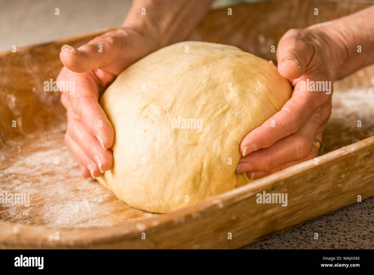 Frau Gestaltung den Teig zu einer Kugel in den antiken Teig Trog, in der Vorbereitung für die teigkugeln für ihre Monkey Brot. (MR) Stockfoto