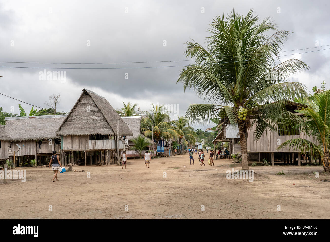 Puerto Miguel, Peru. Native Menschen zu Fuß neben ihren Häusern auf Stelzen gebaut, neben einer Palme im Dorf Puerto Miguel. (Redaktionelle nur verwenden) Stockfoto