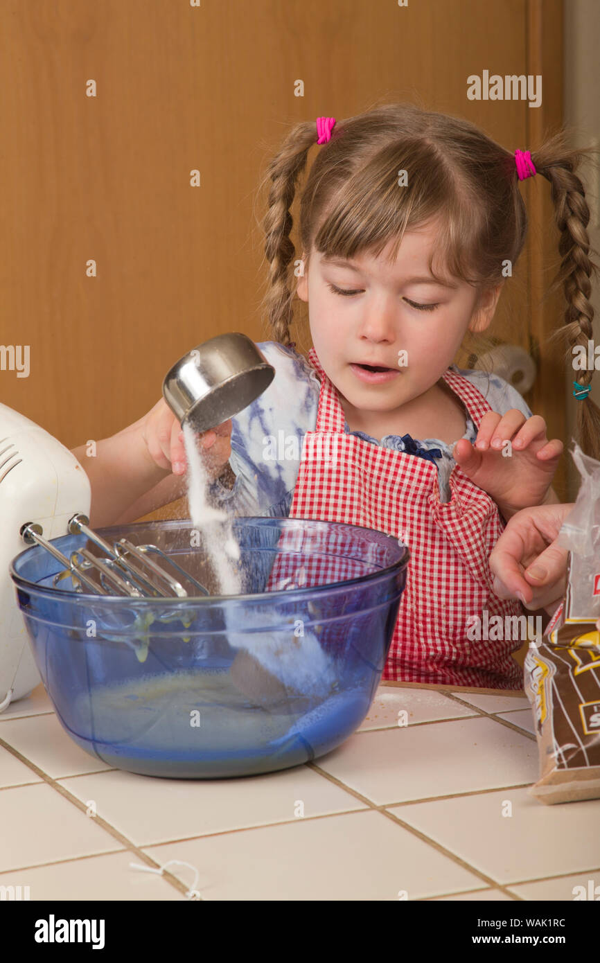 Mädchen Zucker in die Schüssel giessen, wie Sie hilft Karottenkuchen machen. (MR, PR) Stockfoto