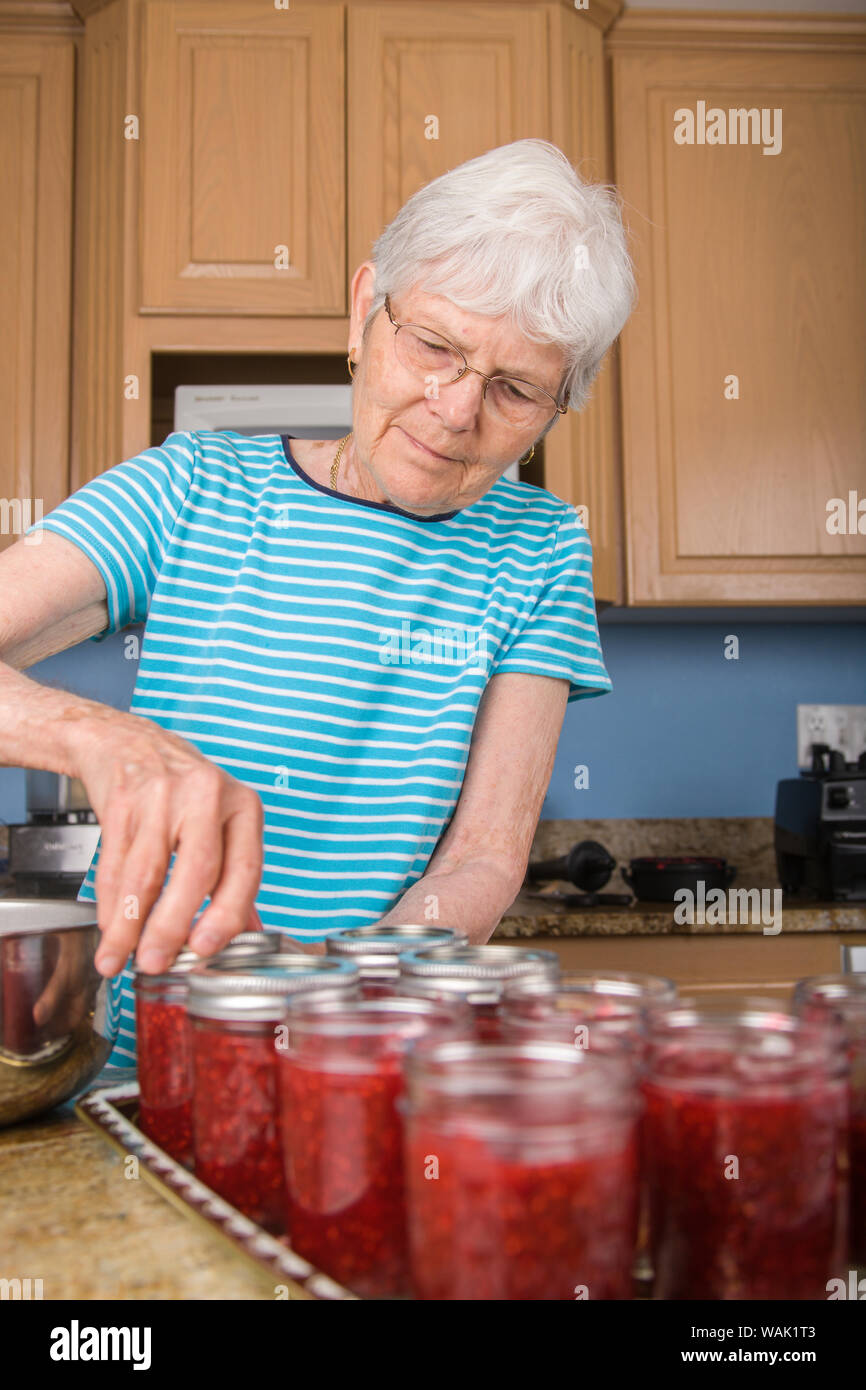 Frau anschrauben Ringe und Kappen der Gläser von himbeermarmelade. (MR, PR) Stockfoto Frau anschrauben Ringe und Kappen der Gläser von himbeermarmelade. (MR, PR) Stockfoto