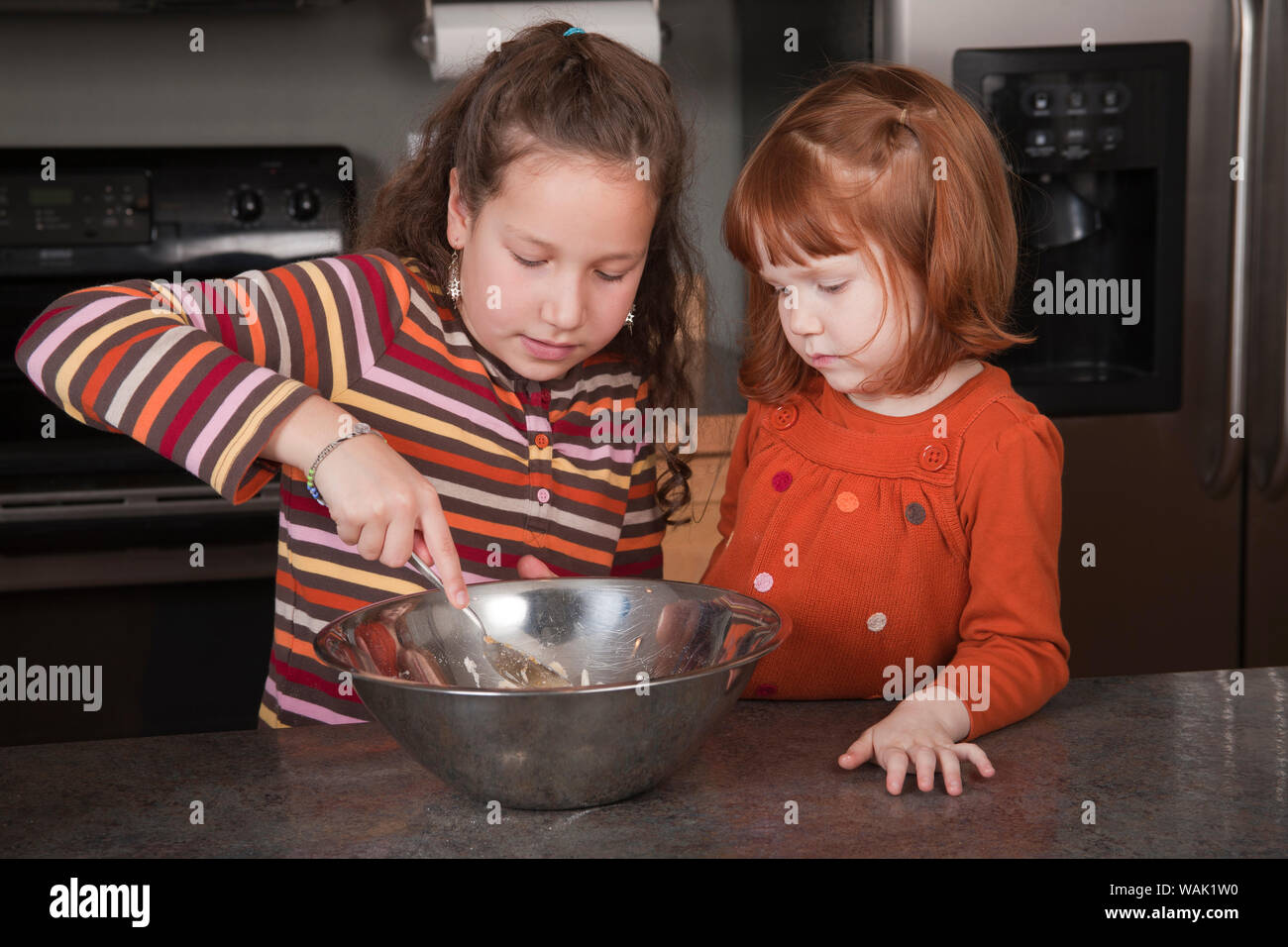Schwestern rühren Plätzchenteig. (MR, PR) Stockfoto