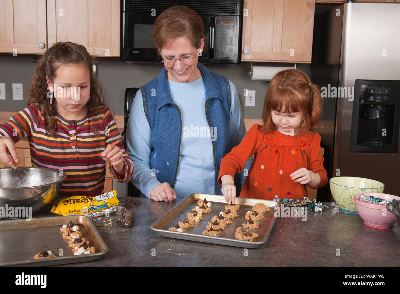 Großmutter und Ihr 4 und 11 Jahre alten Enkelinnen Cookies. (MR, PR) Stockfoto