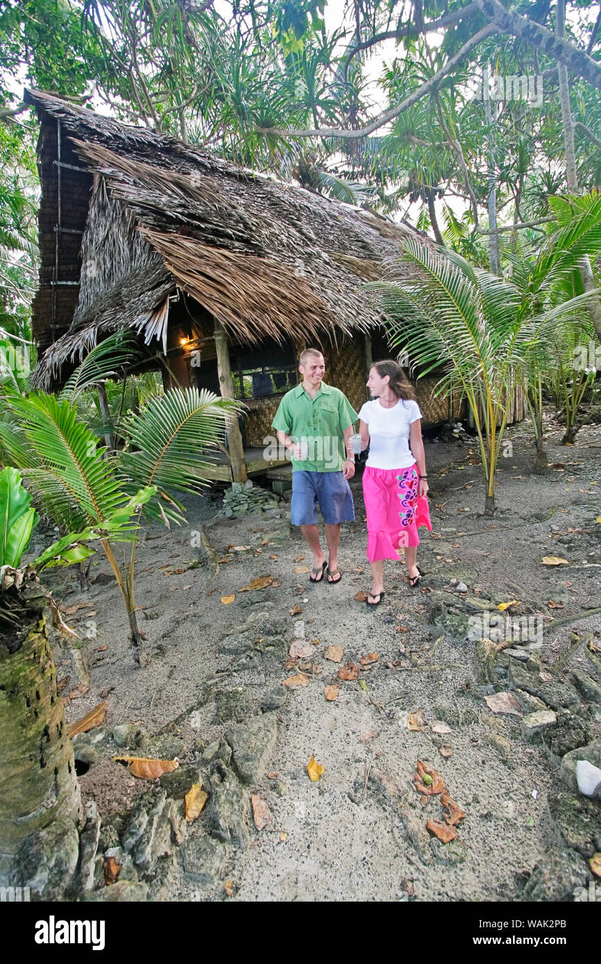 Kosrae, Mikronesien (FSM). Junges Paar Wanderweg von ihren traditionellen Palmen und Bambus thatch Bungalow. Stockfoto